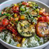 Vibrant sautéed zucchini and peppers atop rice for a Summer Vegetable Bowl, served in a white bowl with fresh basil garnish.