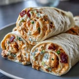 Spicy Buffalo chicken and cream cheese pinwheels wrapped in flour tortillas, perfect for game day appetizers.  