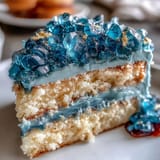 A stunning teal and gold geode graduation cake featuring a carved slice and sparkling sugar crystals.