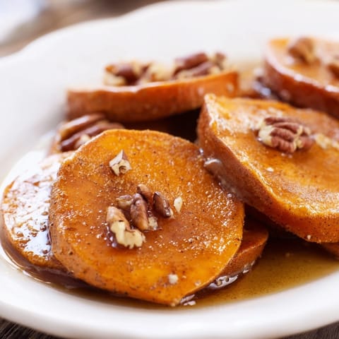 Close-up of baked candied yams, showing tender sweet potato and the rich, sugary glaze.