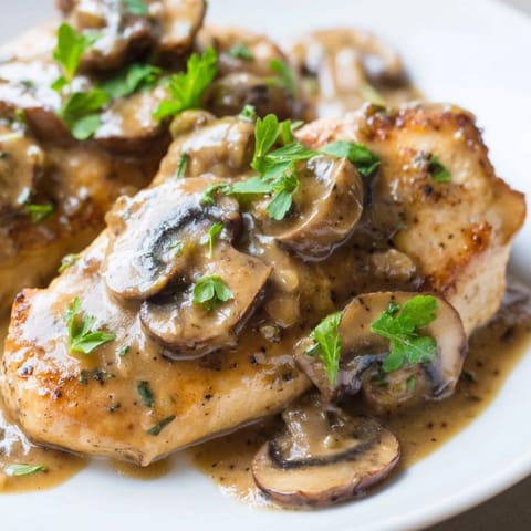 Hearty Creamy Chicken Marsala recipe served with fresh parsley and grated Parmesan for an Italian-American dinner.  