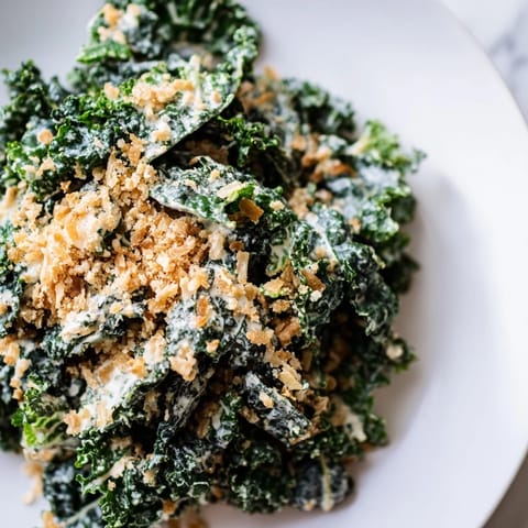 A serving bowl of fresh Garlic Parmesan Kale Salad, highlighting tender kale leaves, shredded Parmesan, and crispy breadcrumbs for a crunchy finish.