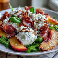 Creamy burrata salad with sweet peaches and prosciutto, drizzled with balsamic glaze.